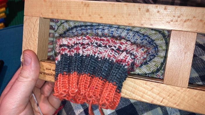 the cuff of the sock coming off the loom - its orange and earthy