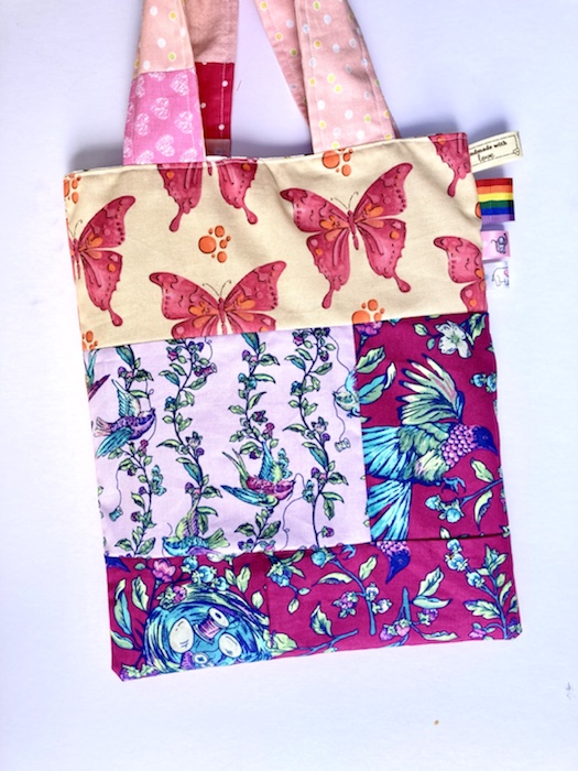 the reverse of the the handmade tote bag has purple birds and butterflies on.