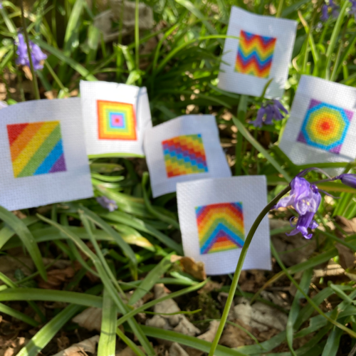 Tiny Rainbow Cross stitch squares in grass